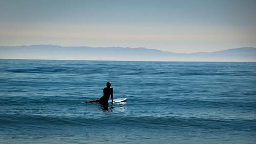 beach landscape photo lens of person surfing board coast